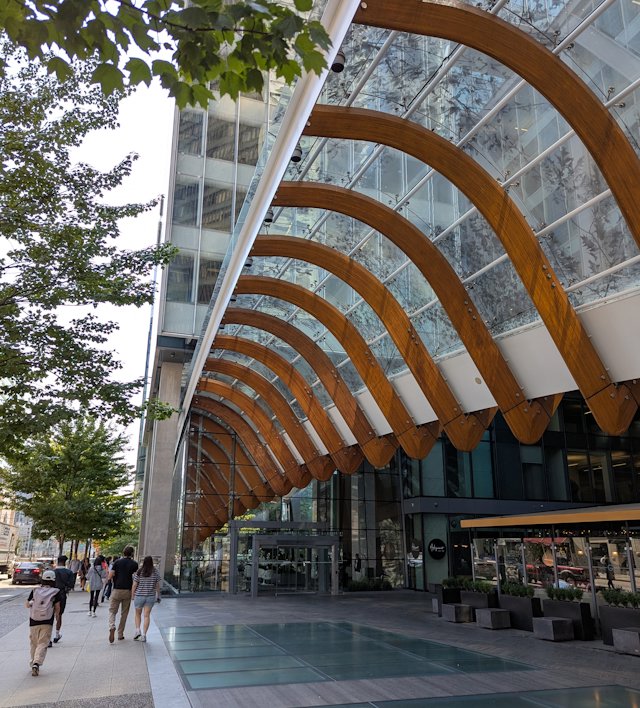 A sidewalk with a curved covering leading into the lower story of a building