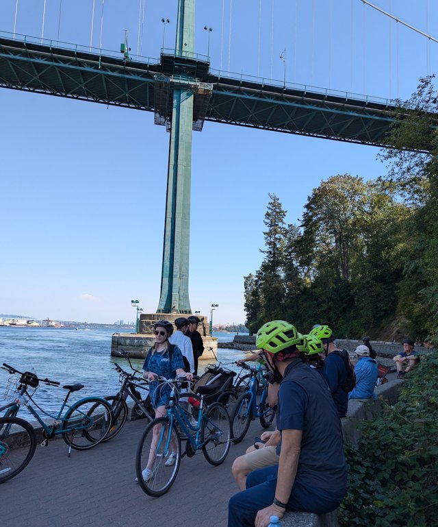 bikers sit on a wall and enjoy a view of the bridge