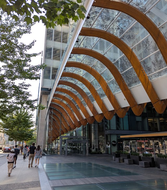 A sidewalk with a curved covering leading into the lower story of a building