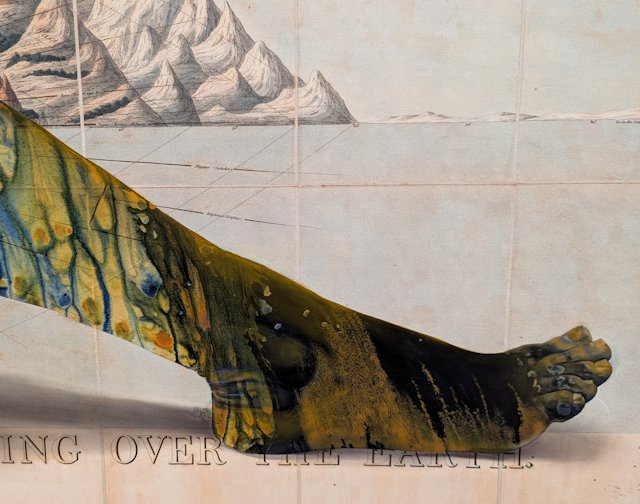 detail of a foot, with oil paint dripping down in front of mountains over water
