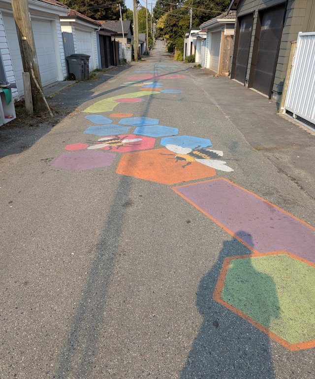 brightly painted hexagons and bees on the pavement of a back street