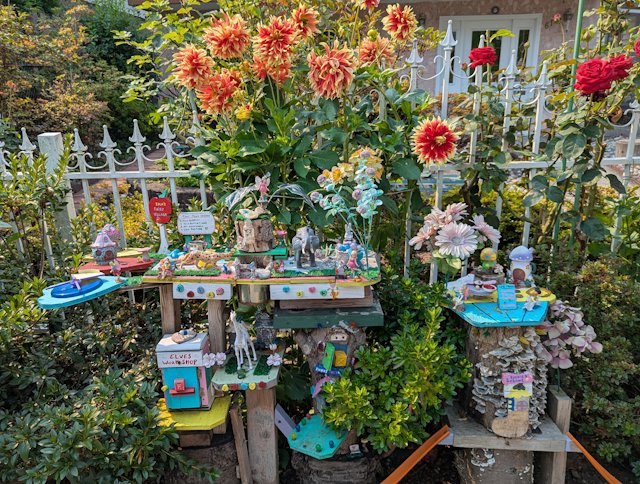 fairy garden with elves workshop and fairy school surounded by yellow and red flowers