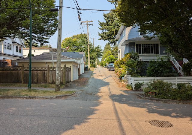 looking across the street at a narrow and terraced backstreet between houses
