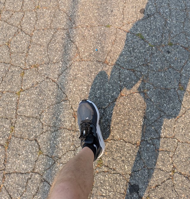 a shoe and leg stepping forward on cracked pavement