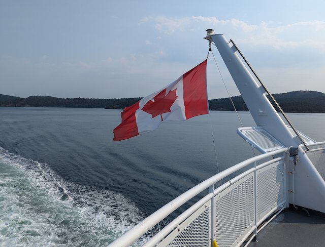 The Candadian flag blowing in the wind behind the ferry