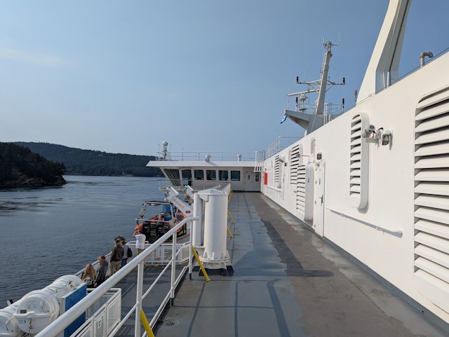 looking forward along the walkway of the top deck with lifeboat and people on the promenade deck below