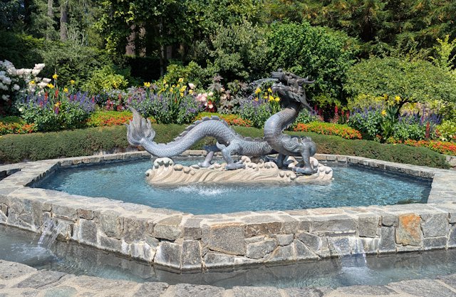 a curved serpent-dragen fountain with water shooting from its mouth