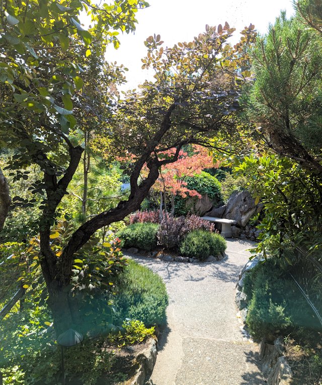 scenic little garden path with a bench atop a raised rock within sunken gardens