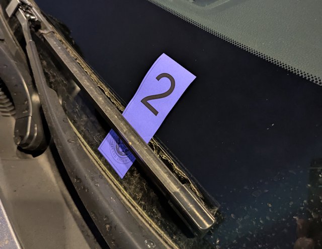 purple tag with number 2 on it tucked under windshield wiper