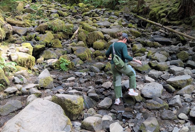 Stacey stepping across some rocks in a mostly dried-up stream